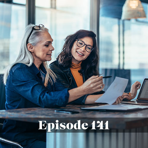 Two women discussing strategic plans on their computers and on paper